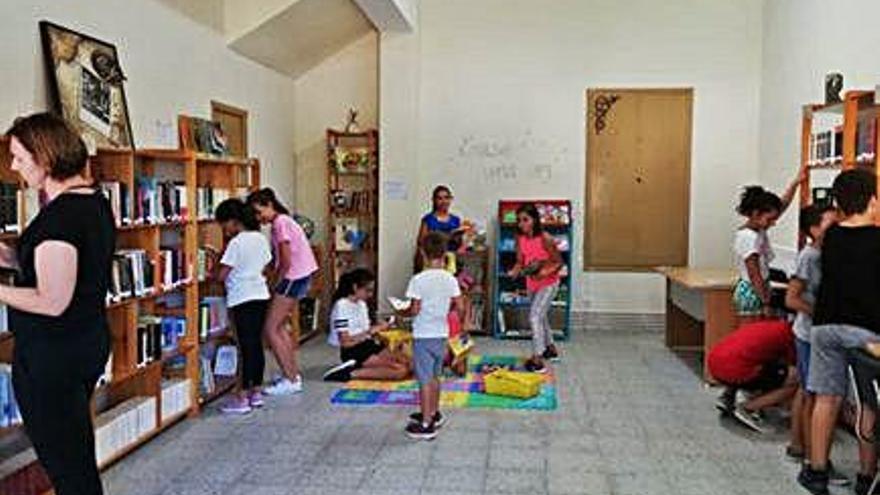 Varios niños y una vecina colocan los libros donados para la Biblioteca de Peleagonzalo.