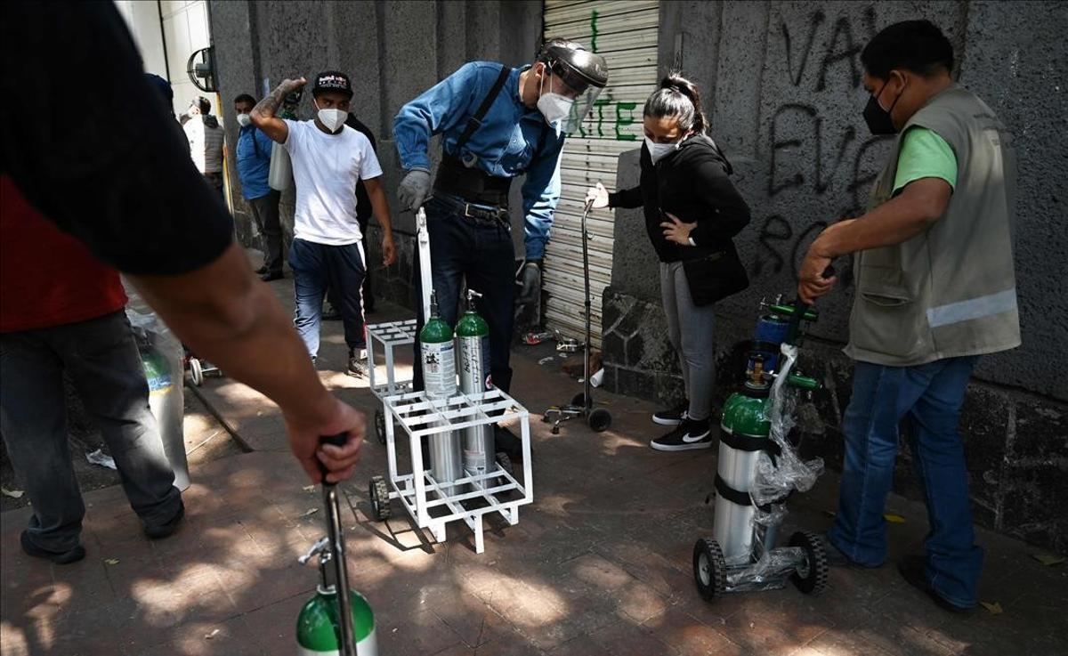 Un empleado de la compañía Infra Medica reparte botellas de oxigeno a la gente que guarda cola en México D.F.