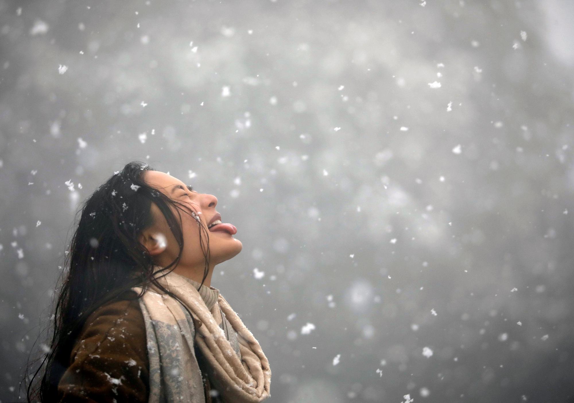 Una mujer intenta atrapar copos de nieve