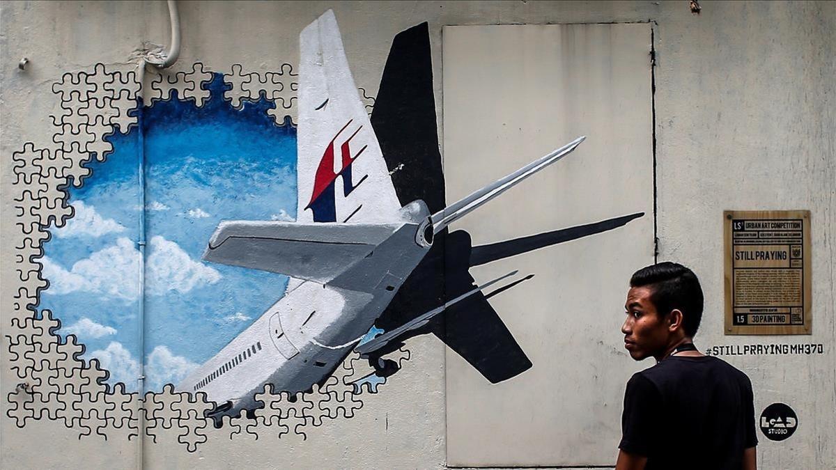 Un joven pasa por delante de un  mural del vuelo MH370 de Malaysia Airlines en Kuala Lumpur el 6 de marzo del 2015.