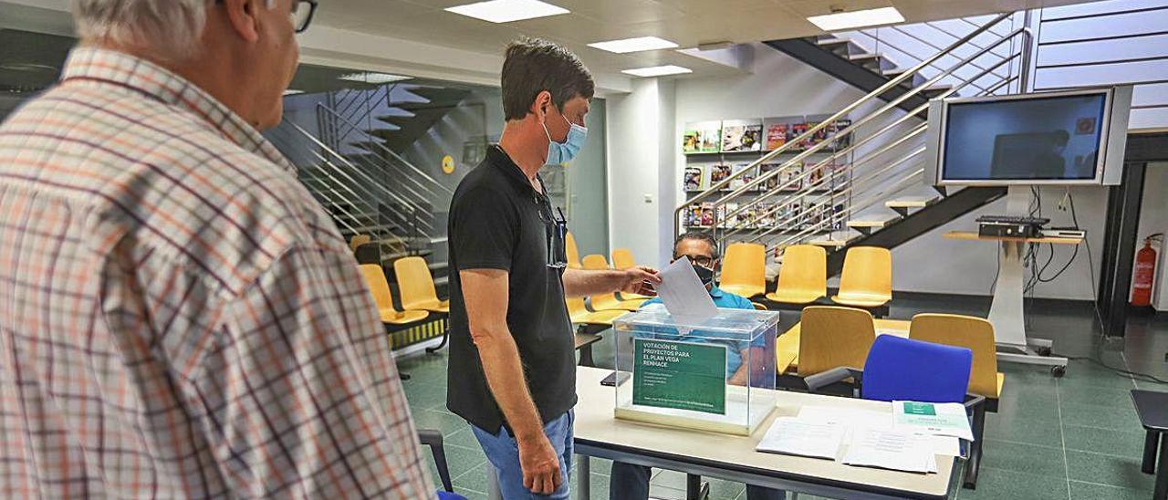 Dos vecinos de Orihuela votan ayer en las urnas instaladas en el aula CAM los proyectos para evitar inundaciones como la de su ciudad.