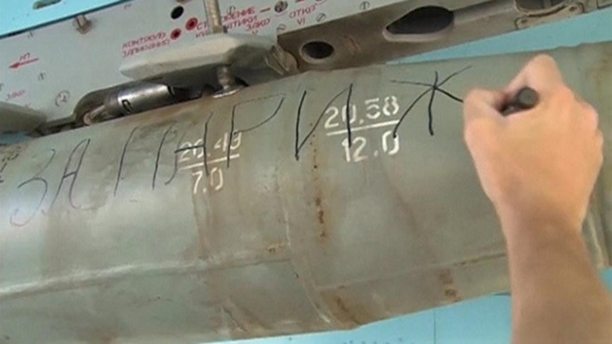 Handout of a still image taken from video footage released by Russia's Defence Ministry showing a ground crew member writing words &quot;For Paris&quot; on bomb on a Russian military jet at Hmeimim air base in Syria