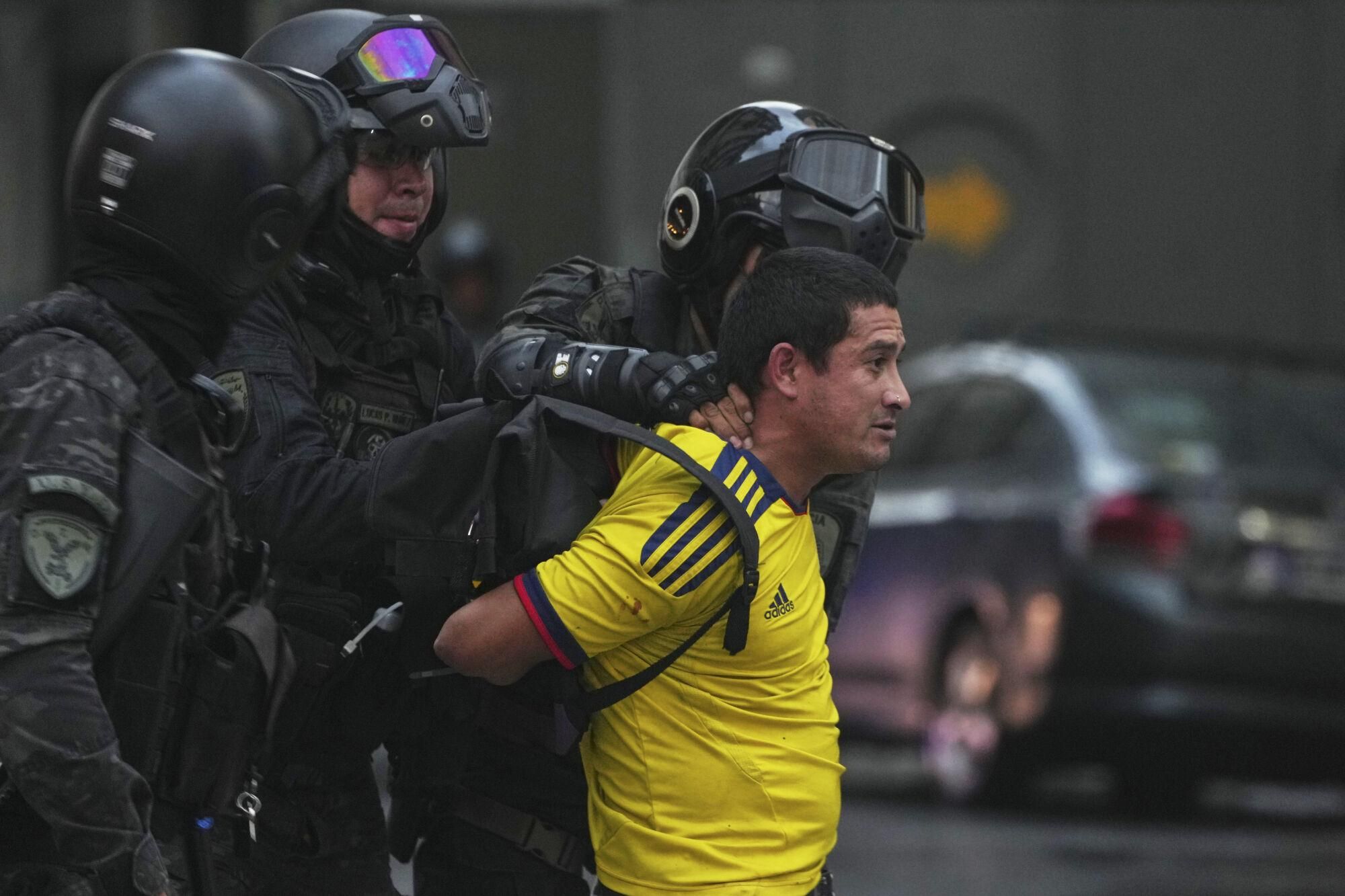 Police detain a soccer fan who joined retirees protesting for higher pensions and against austerity measures implemented by Javier Milei's government in Buenos Aires, Argentina, Wednesday, March 12, 2025. (AP Photo/Natacha Pisarenko)