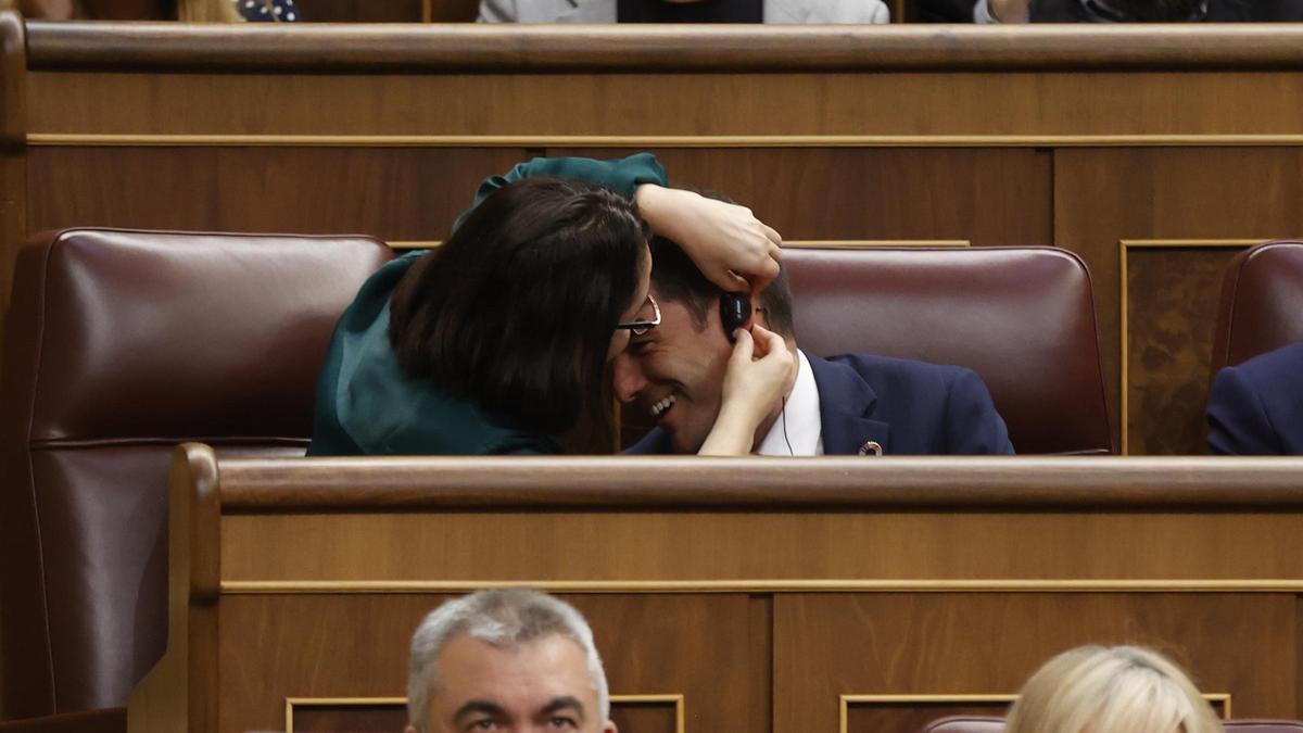Eine Parlamentarierin bringt bei einem Kollegen einen Ohrstöpsel an