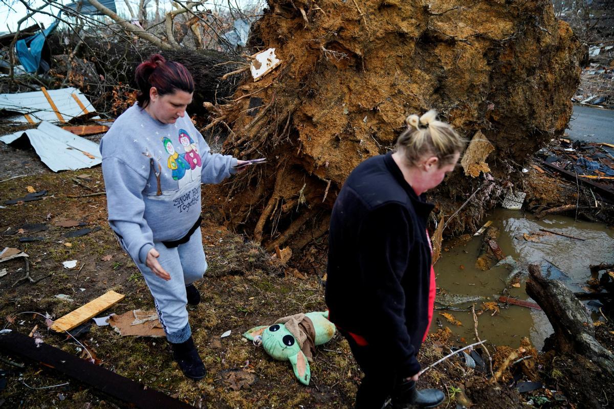 Amy Meno y Brooklyn Rogers buscan sus pertenencias después de que un devastador brote de tornados arrasó varios estados de EE. UU.