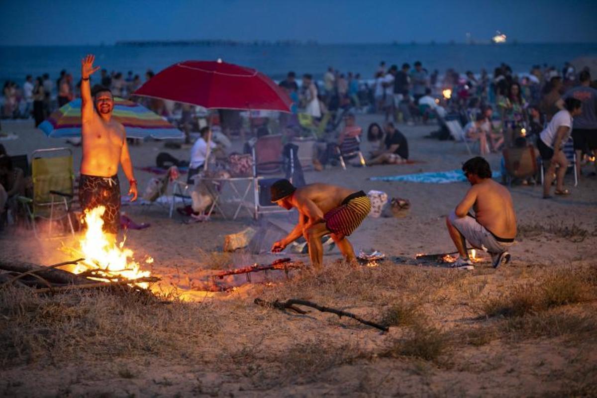 Grupo de personas controlando el fuego de la hoguera el dia de San Juan.