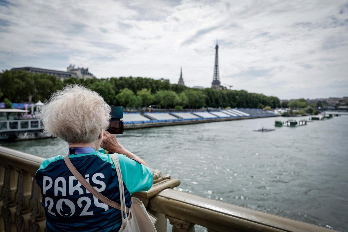 Un voluntario de París 2024 toma una fotografía en el puente de los Inválidos, junto a las tribunas instaladas en el río Sena, en vísperas de la ceremonia de apertura de los Juegos Olímpicos de París 2024
