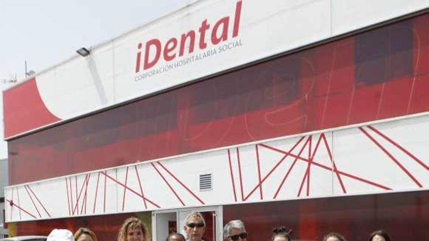 Un grupo de afectados aplaude a las puertas de la clínica de iDental en Gijón mientras los agentes de la Policía judicial registran su interior.
