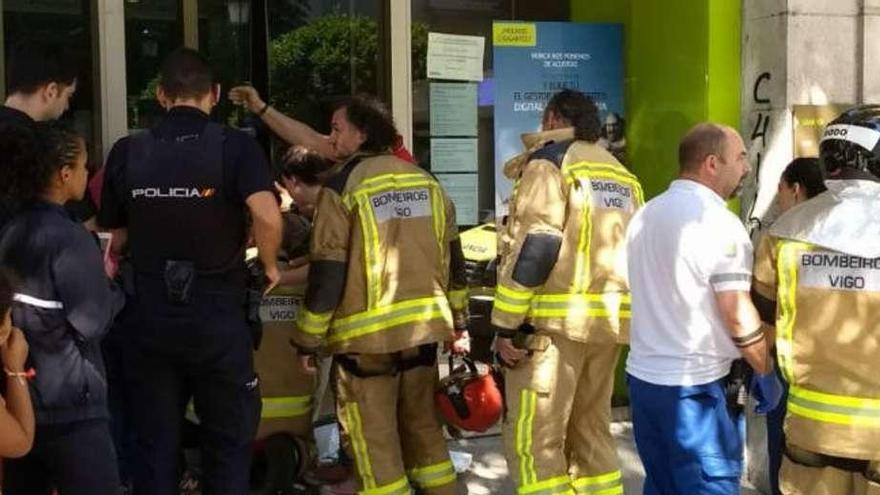 Bomberos y policías delante de la puerta de la sucursal. // FdV