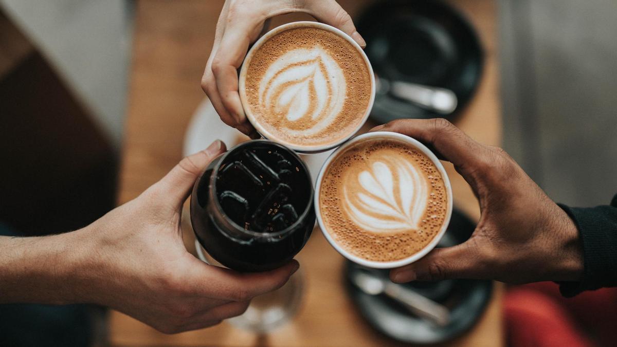 Tres personas brindando con bebidas de café.