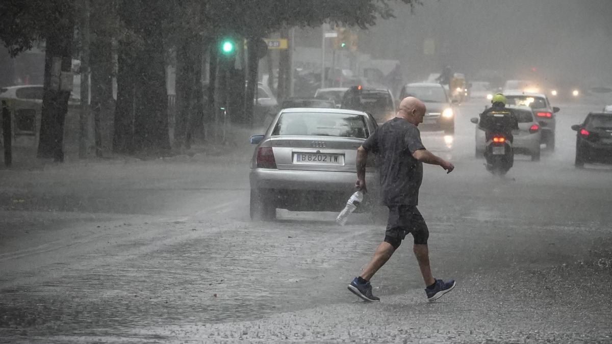 Coches, bicicletas y peatones sortean grandes charcos de agua acumulada en la calle Perú de Sant Martí durante la tormenta de lluvia