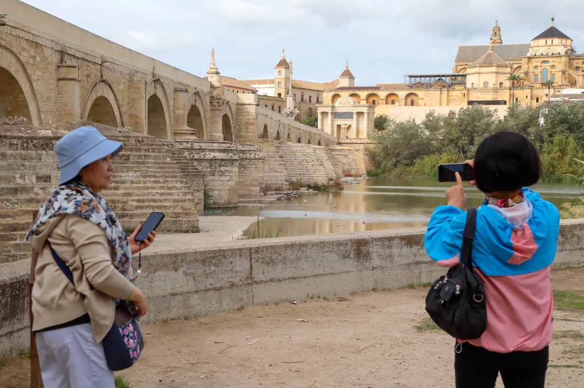 Dos turistas hacen una fotografía de la Puerta del Puente y la Mezquita-Catedral, junto al Puente Romano. El nivel del río en noviembre era muy bajo por la sequía.