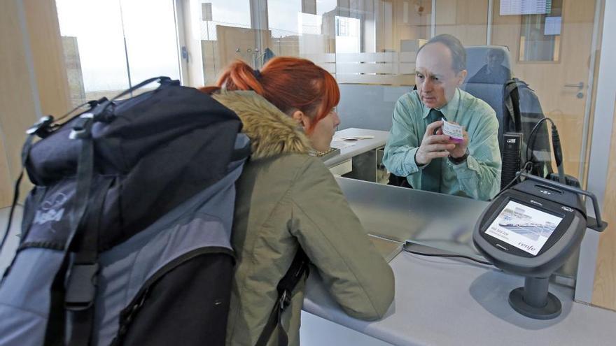 Un empleado de las taquillas de Urzáiz despacha un ticket a una usuaria. // M.G.B.