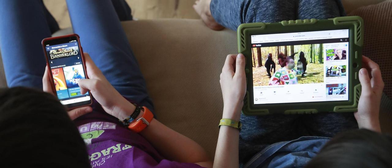 Dos niños, con la tablet y el móvil en sus casas.