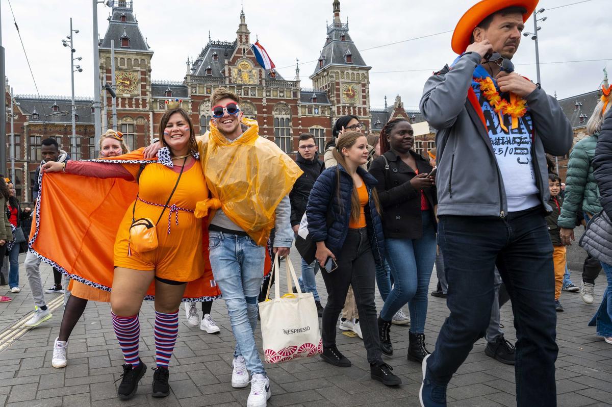 Ciudadanos vestidos con motivos naranjas llegan a la estación central de Amsterdam para celebrar el Día del Rey.