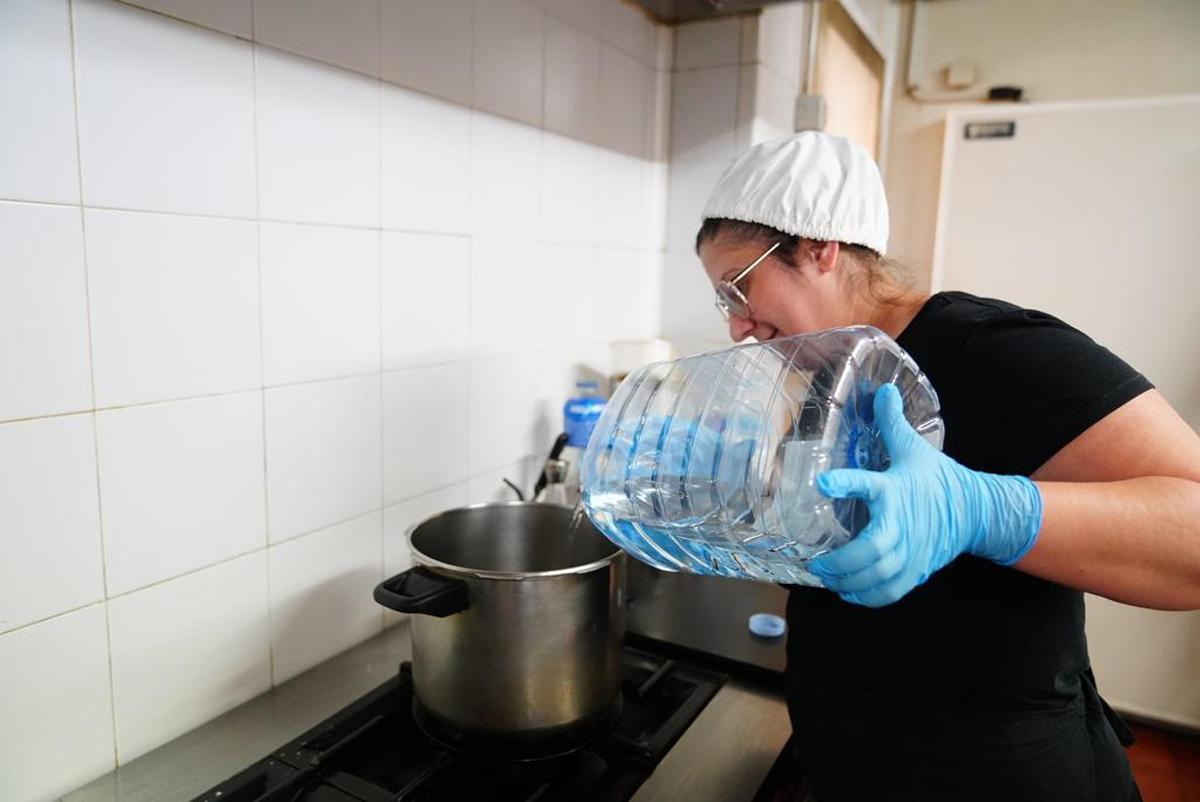 Una cocinera utiliza agua embotellada para preparar la comida.