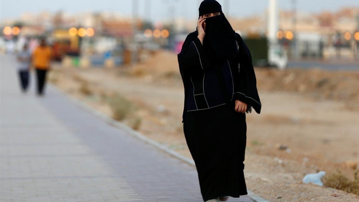 Una mujer saudi habla por teléfono mientras camina por una calle de Riad.