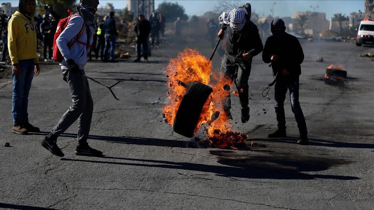 Manifestantes palestinos queman un neumático en protesta por la decisión de EEUU, en Ramalá, este martes 26 de diciembre.