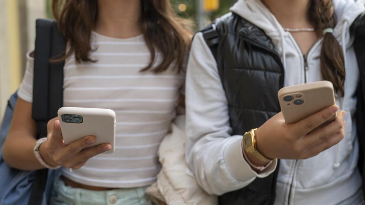 Jóvenes atentos a las pantallas de sus móviles a la salida del instituto