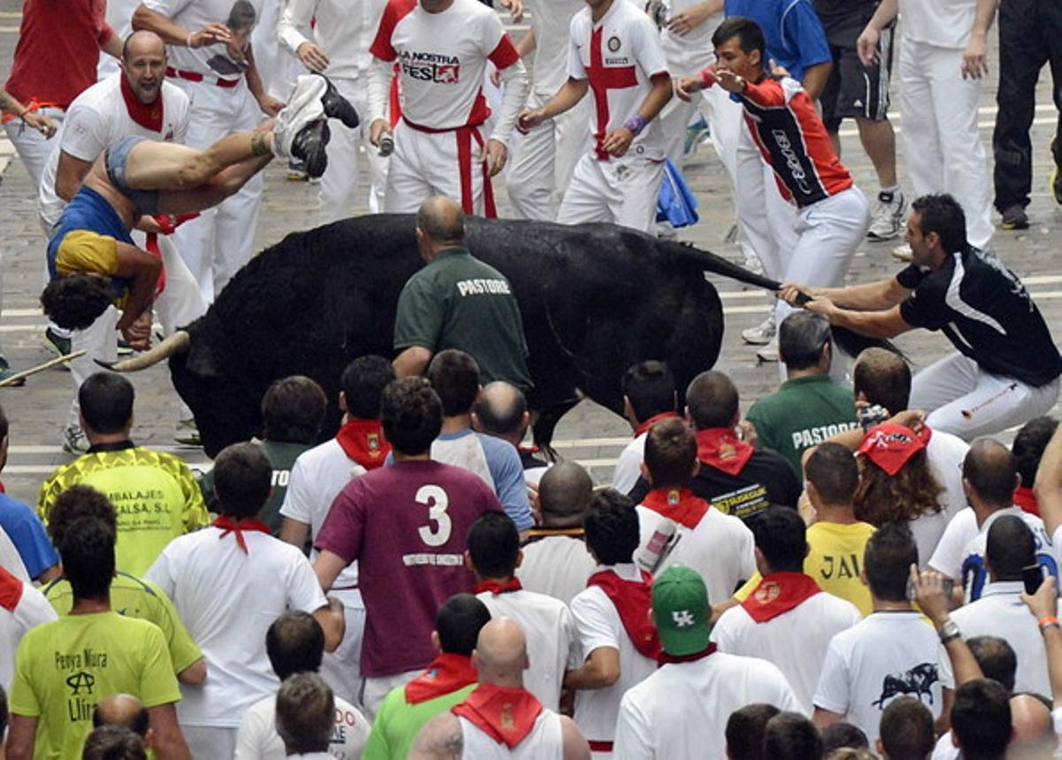 Un jove és envestit per un toro al carrer Estafeta durant el sisè ’encierro’ dels ’sanfermines’.