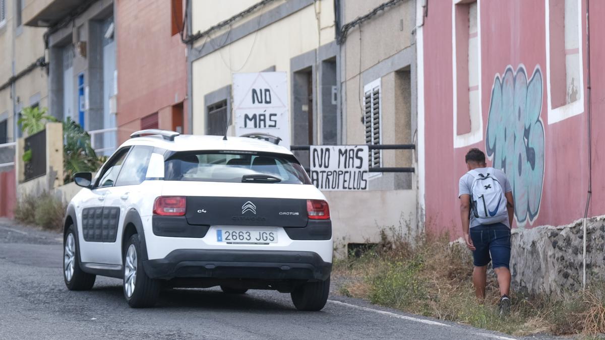 Un joven camina por Almatriche entre carteles reclamando una solución a los atropellos.