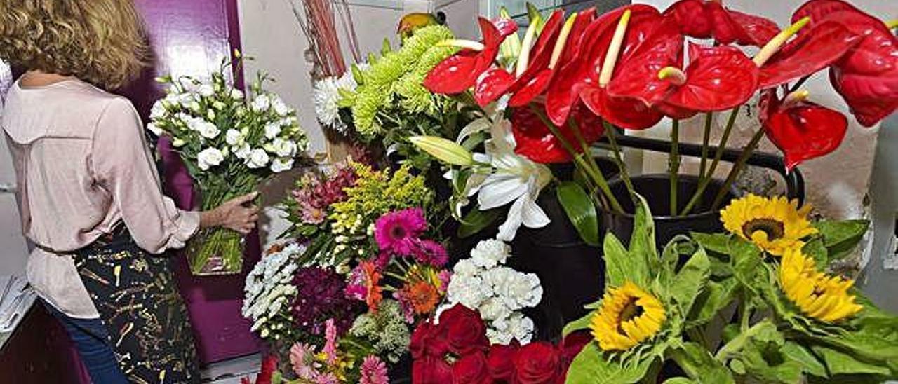 Una floristera coloca flores en su expositor de su establecimiento.
