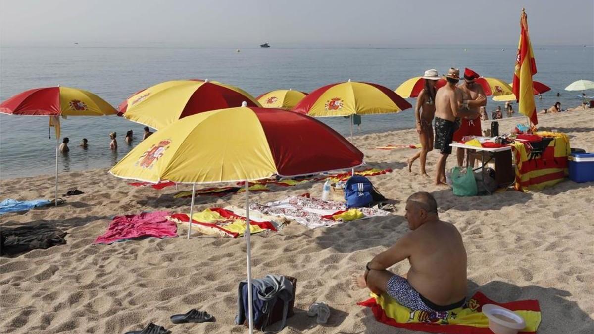 Plantan sombrillas con la bandera de España en una playa de Barcelona