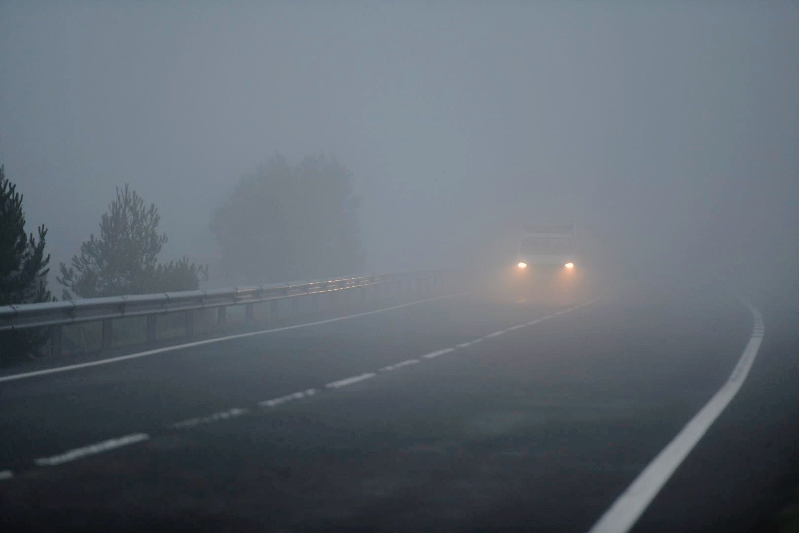 Un coche circula bajo la niebla en una carretera del Pallars Jussà