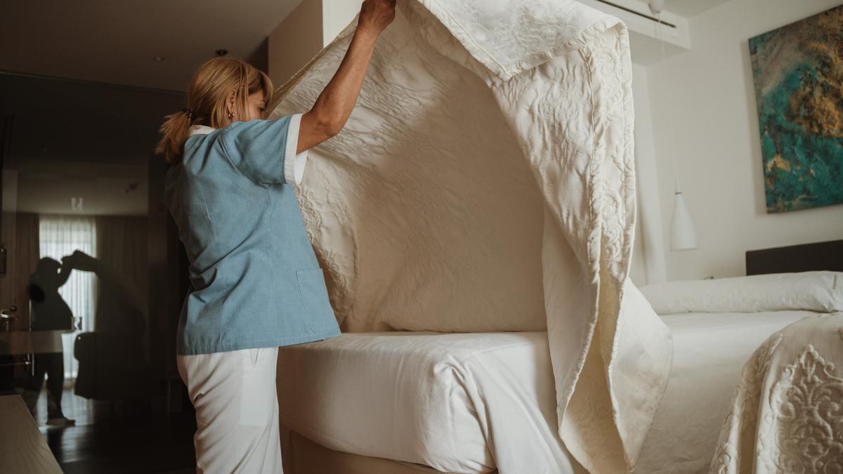 Una camarera de pisos hace una cama con mecanismo elevable en un hotel de Mallorca.