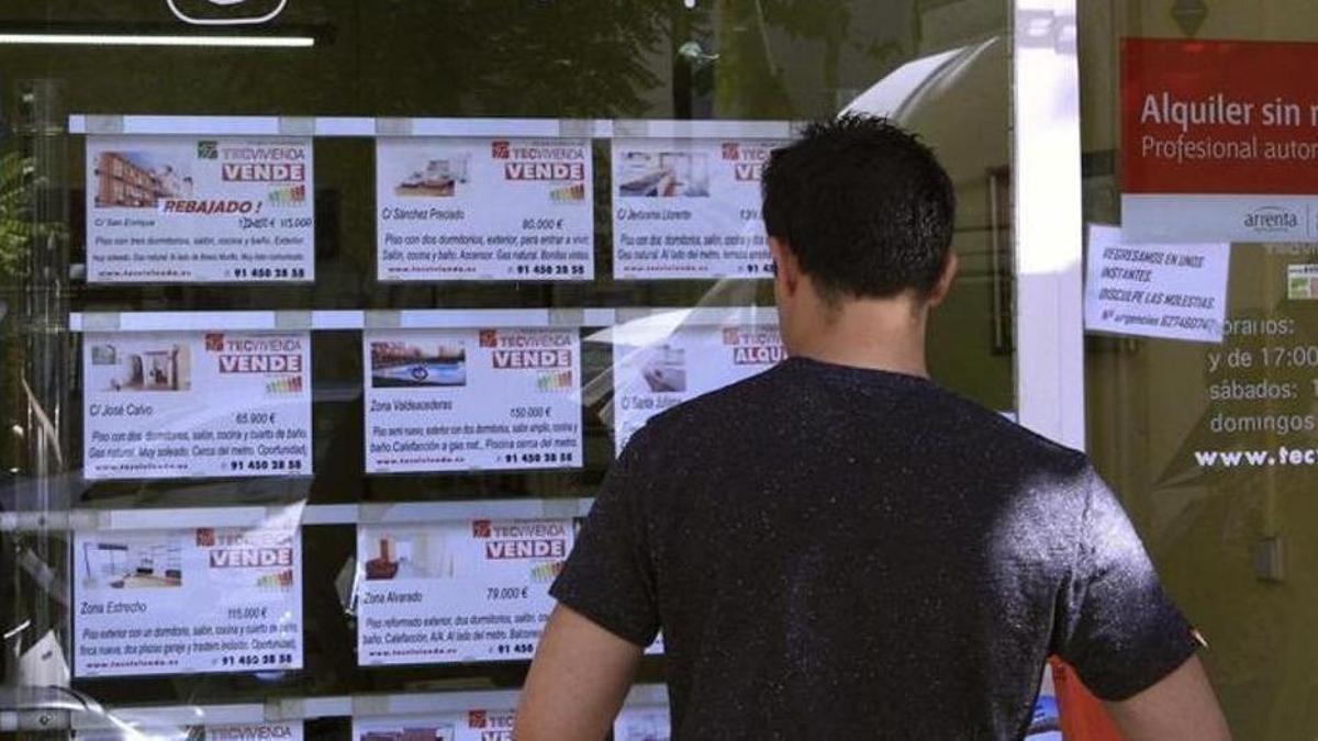 Un home revisa les ofertes de pisos a la venda fora d'una immobiliària