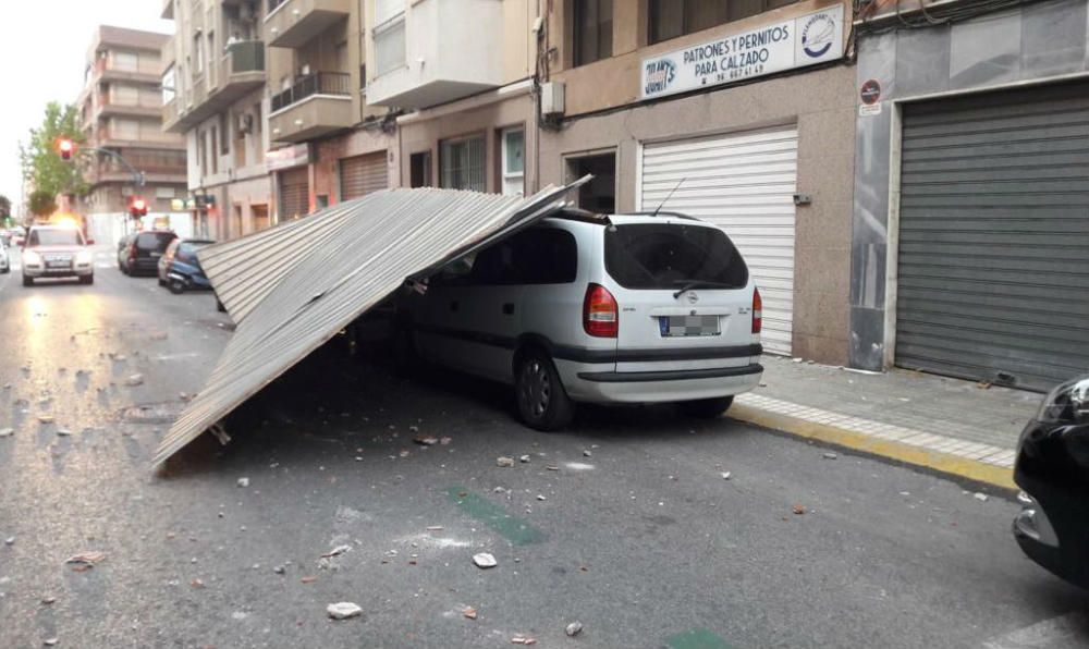 Un coche dañado por la caída de una cubierta metálica por el viento