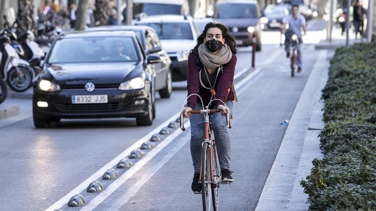 Una ciclista circula por el carril bici de Diagonal protegida por una mascarilla antipolución