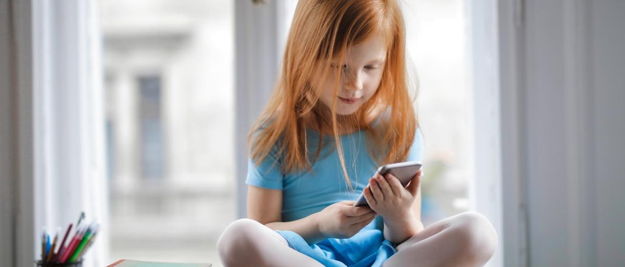 Una niña juega con un teléfono móvil