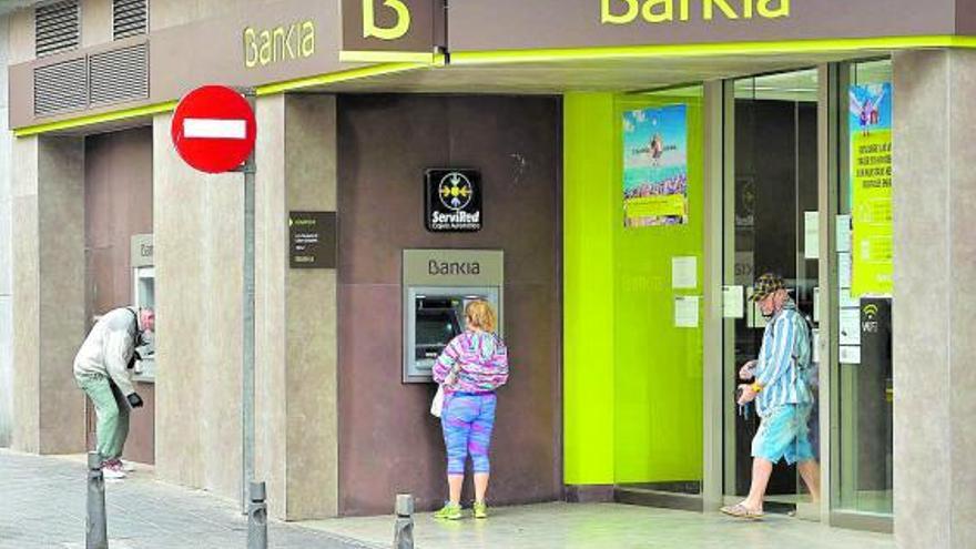 Varias personas hacen uso de un cajero de Bankia en la calle La Naval de la capital gran canaria . | | E.D.