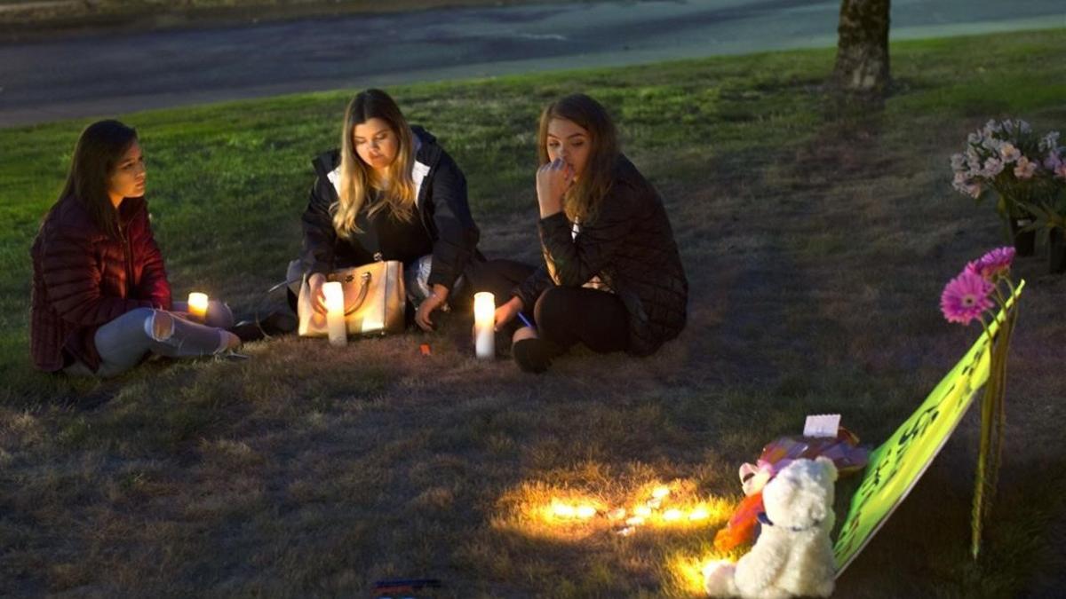 Unas jóvenes encienden velas en memoria de las víctimas del tiroteo en Burlington.