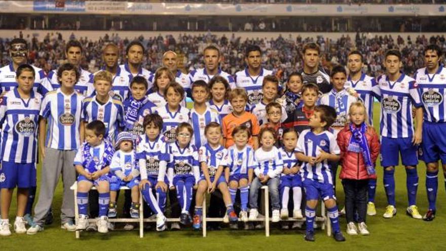 Los once jugadores que formaron de salida ante el Sevilla, como en tres partidos anteriores, posan con un grupo de niños. / juan varela