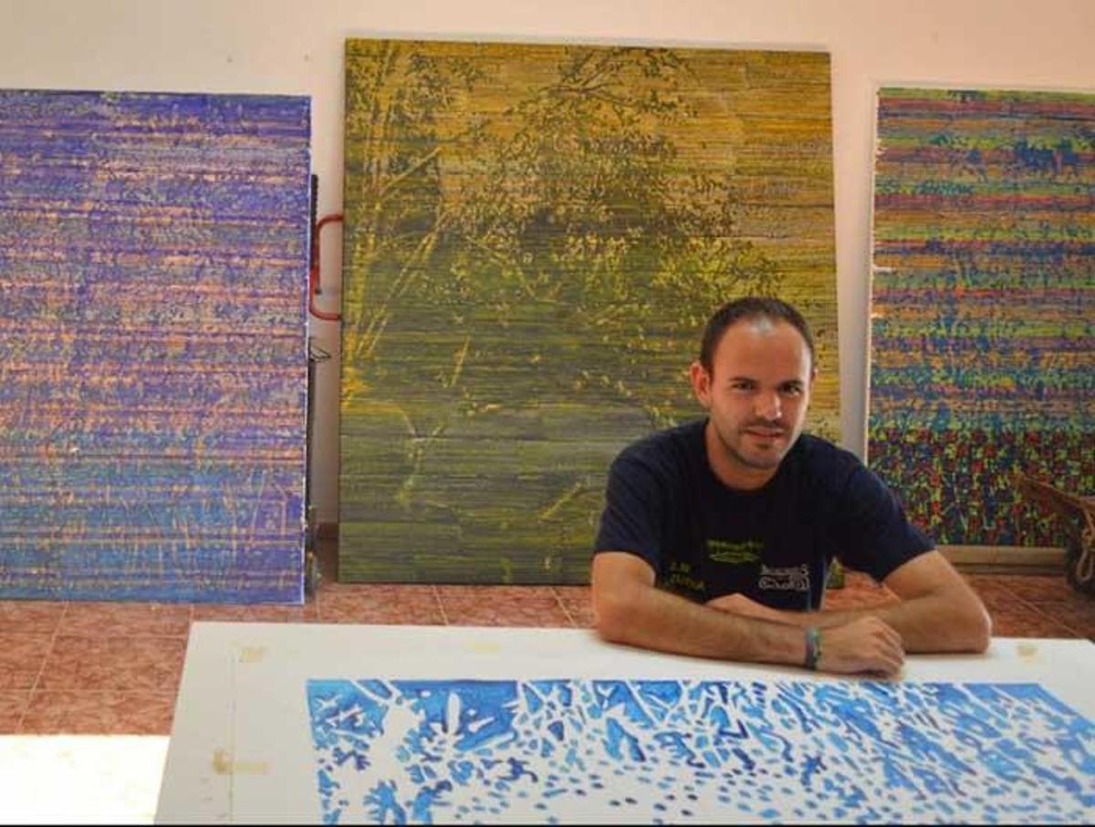 Arriba, Federico Miró con sus obras a su espalda en el estudio.
