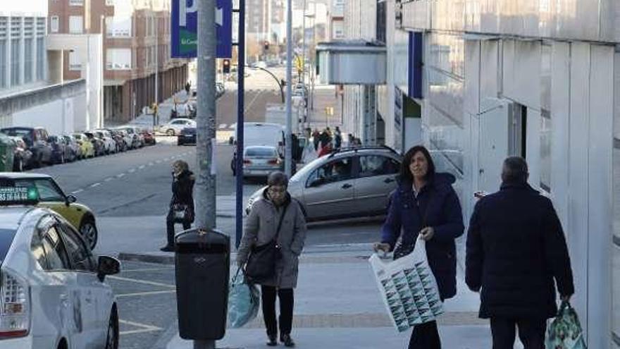 Varias personas salen de un centro comercial de Gijón.