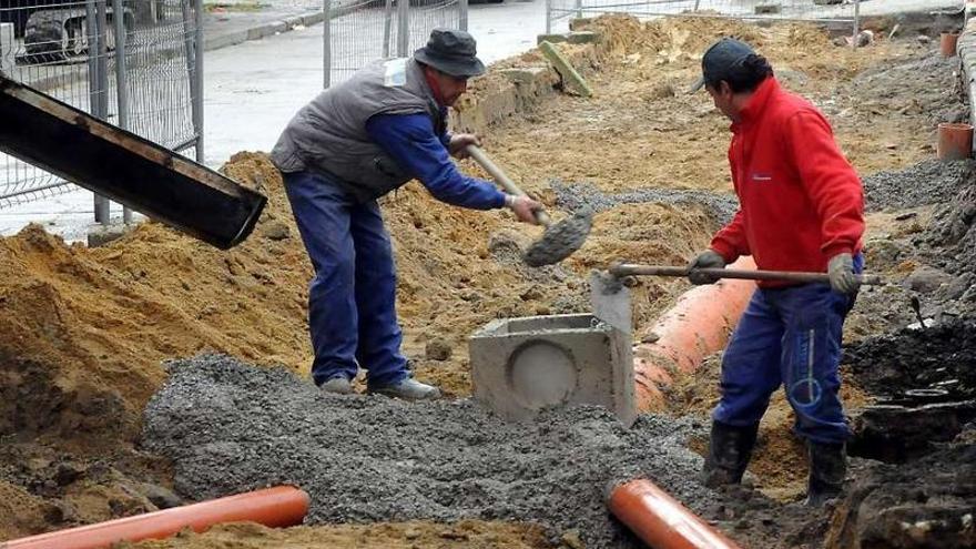 Dos operarios trabajan en una obra de saneamiento en el casco urbano.