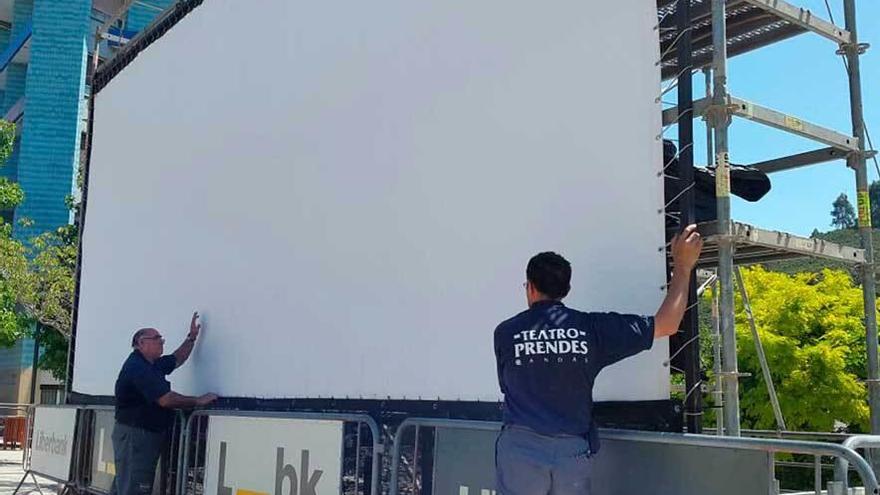 Los operarios, instalando la pantalla para el ciclo de cine al aire libre, ayer, en Les Conserveres.