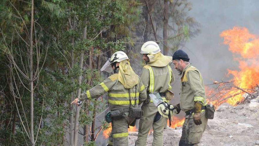 Tres brigadistas en la zona del incendio con las llamas de fondo. // Gonzalo Núñez