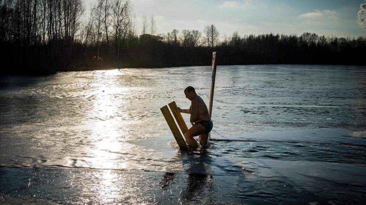 Un creyente ortodoxo sale de un hoyo de hielo en Svyatoye, en las afueras de Moscú