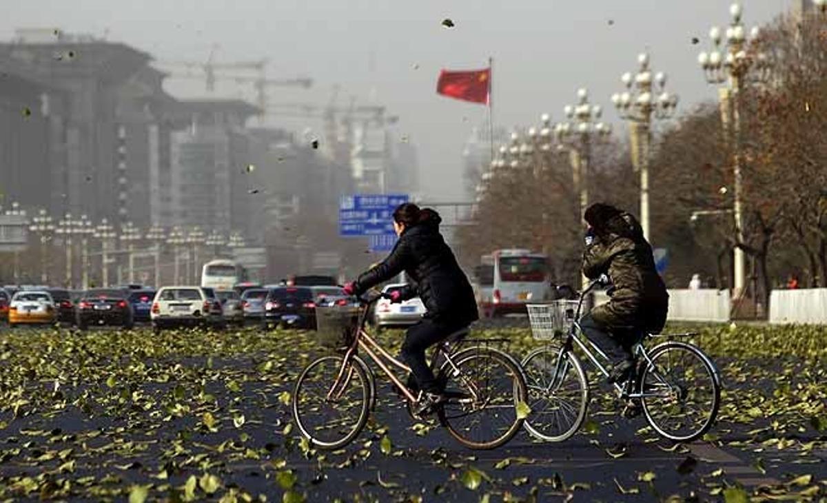 Dos ciclistes travessen l’Avinguda Chang’an enmig d’un vendaval al centre de Beijing (Xina).