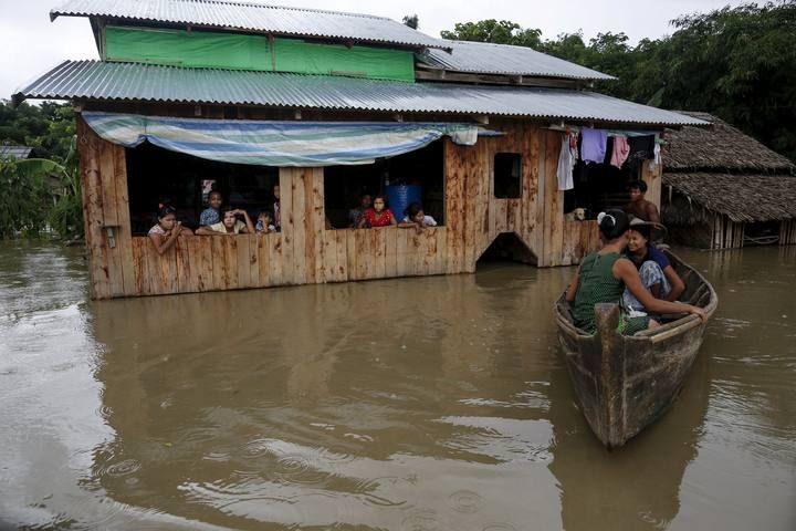 Flood victims wait at their home in a flooded village outside Zalun Township, Irrawaddy Delta