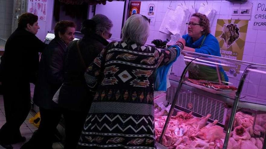 Varias mujeres compran en uno de los puestos del Mercado de Abastos.