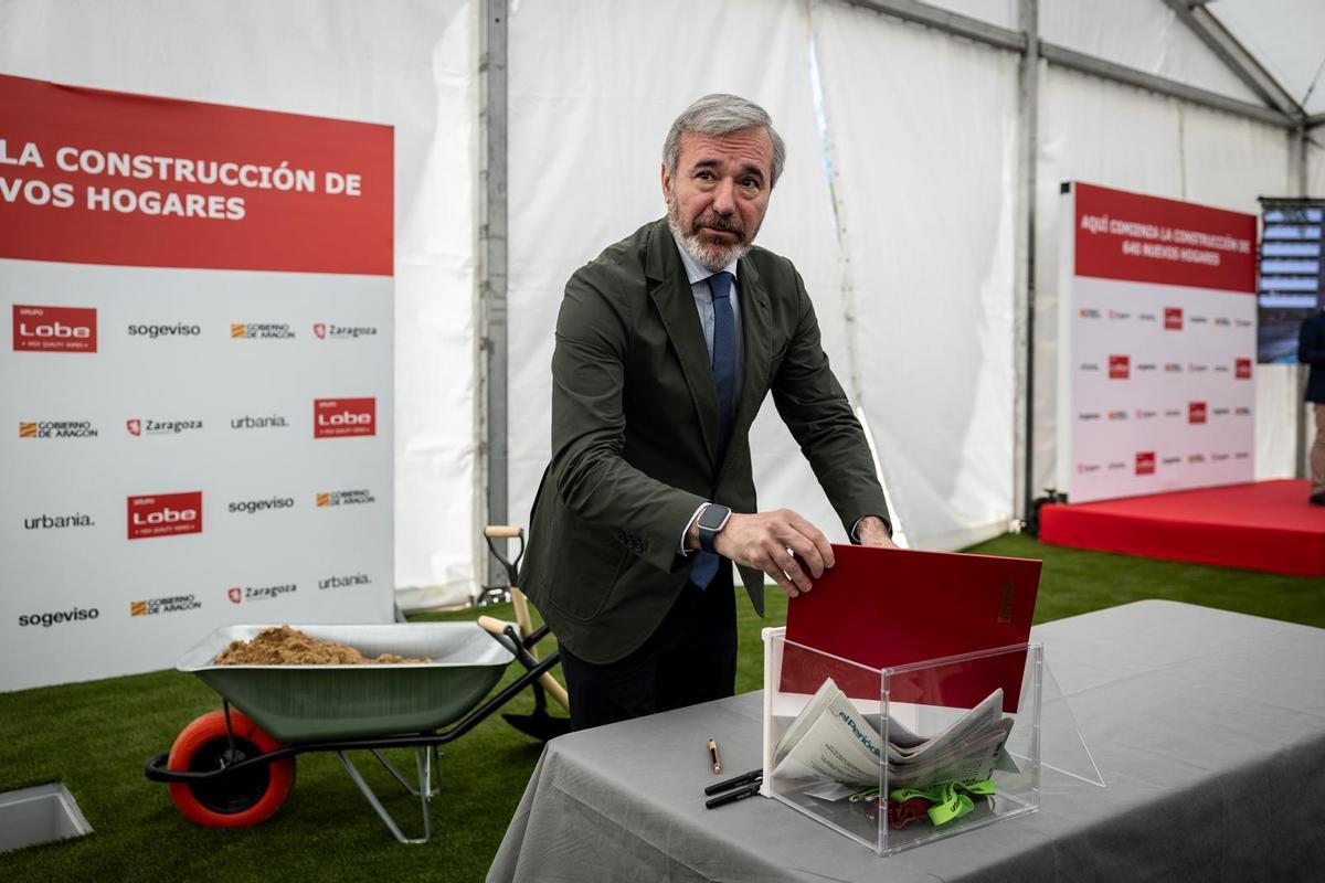 El presidente de Aragón, Jorge Azcón, metiendo el acta de firmas en la urna que sirve como primera piedra de la promoción, con un ejemplar de EL PERIÓDICO del día de hoy.