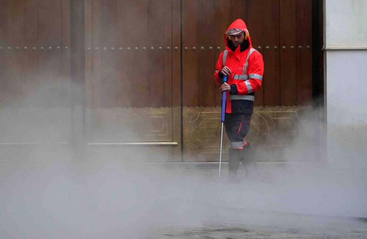 Un operario realiza tareas de quitar la cera de Semana Santa de las aceras de la ciudad