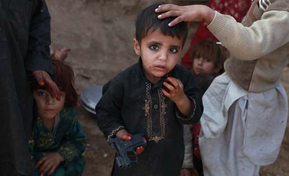 En nen de tres anys aguanta una arma de joguina, mentre juga als afores d’Islamabad (Pakistan).