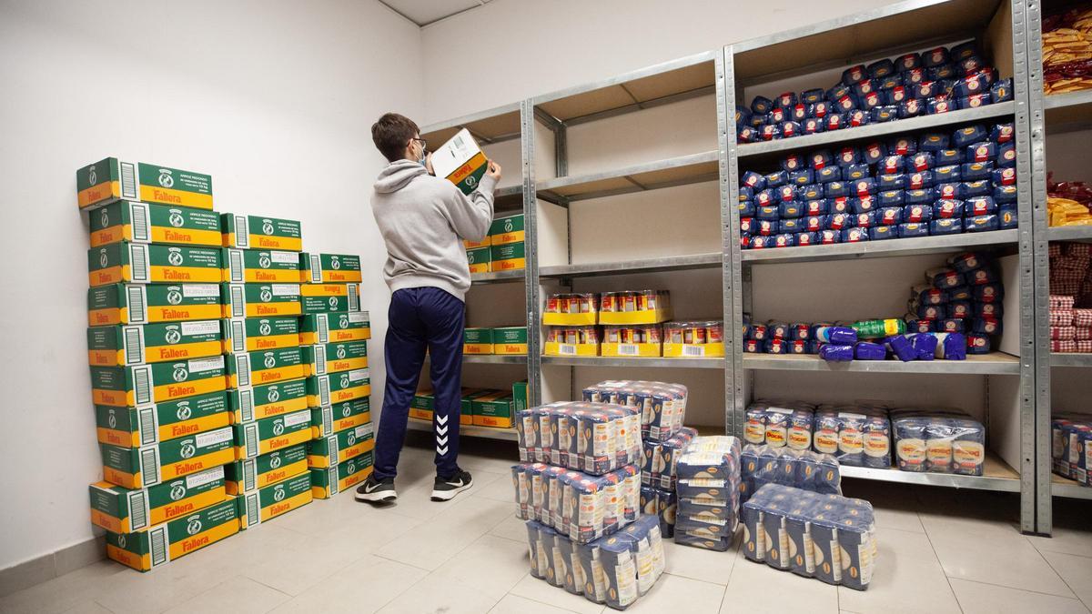 Un voluntario de la ONG repone productos en las estanterías.