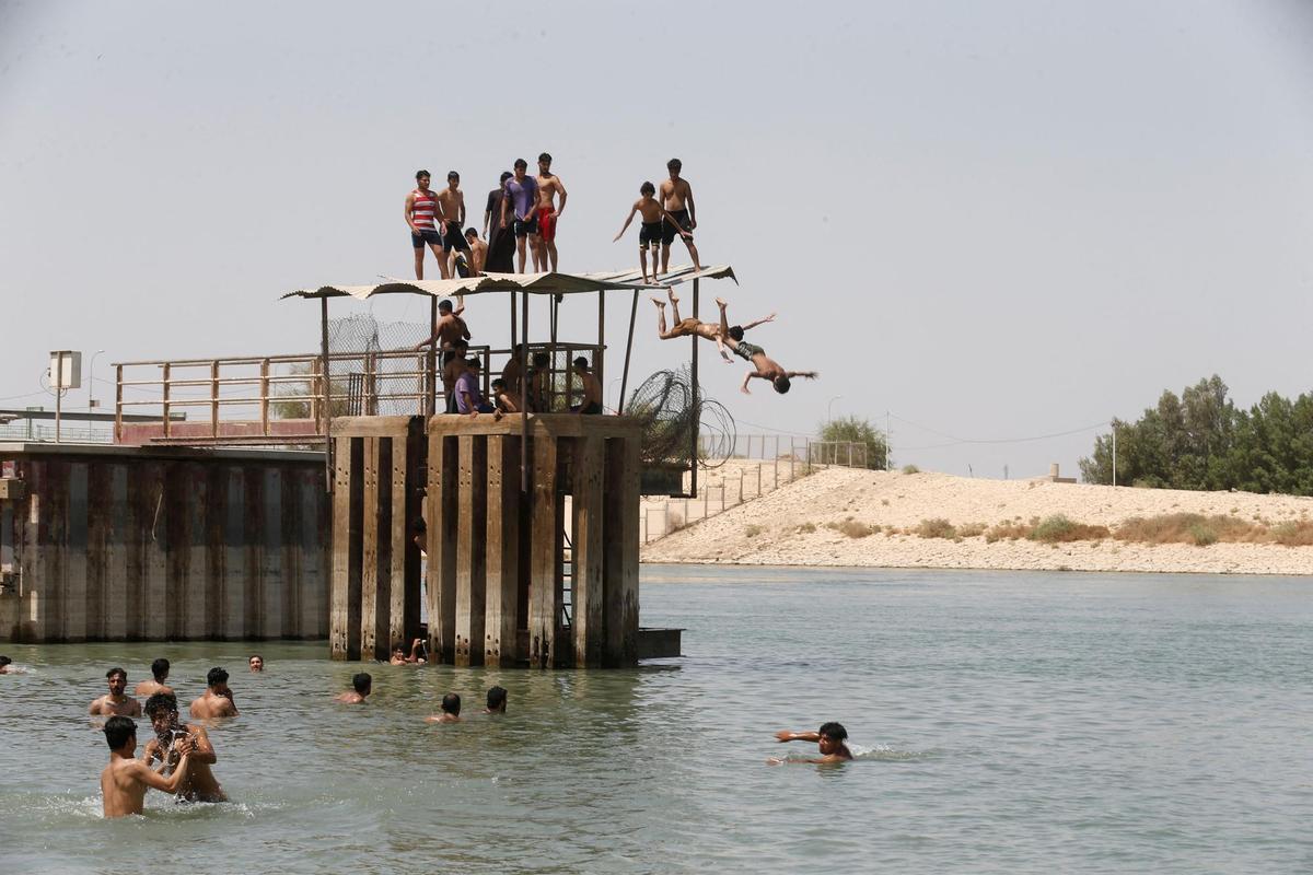 People take a swim and cool off into the Euphrates river, amid increased temperatures, in the holy city of Najaf